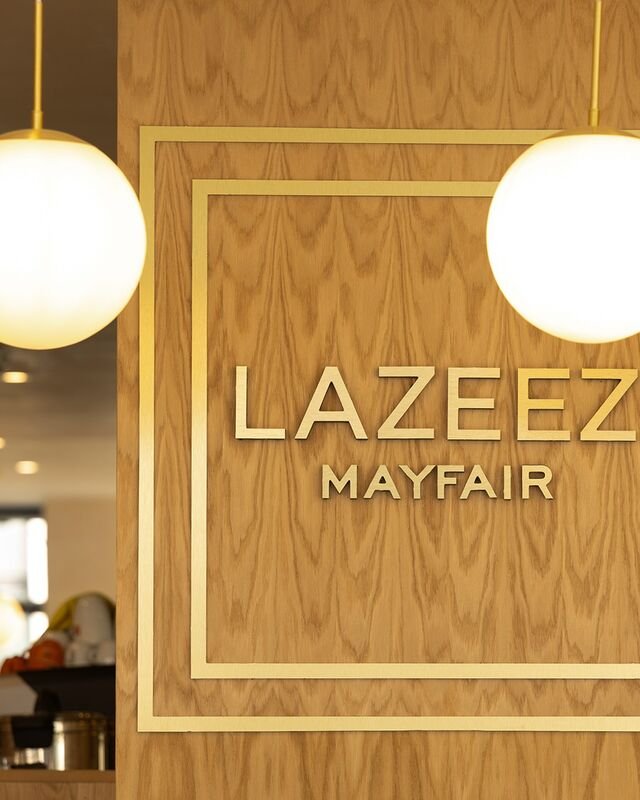 Brass Lazeez Mayfair lettering on the oak panelled feature wall inside the restaurant