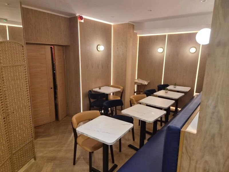 Finished dining area with oak panelling, wall lights and marble topped tables