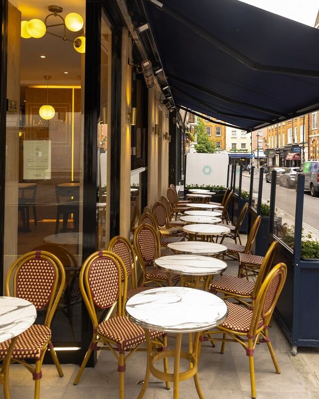 A finished MP Design restaurant interior, with bistro seating and marble topped tables under an awning